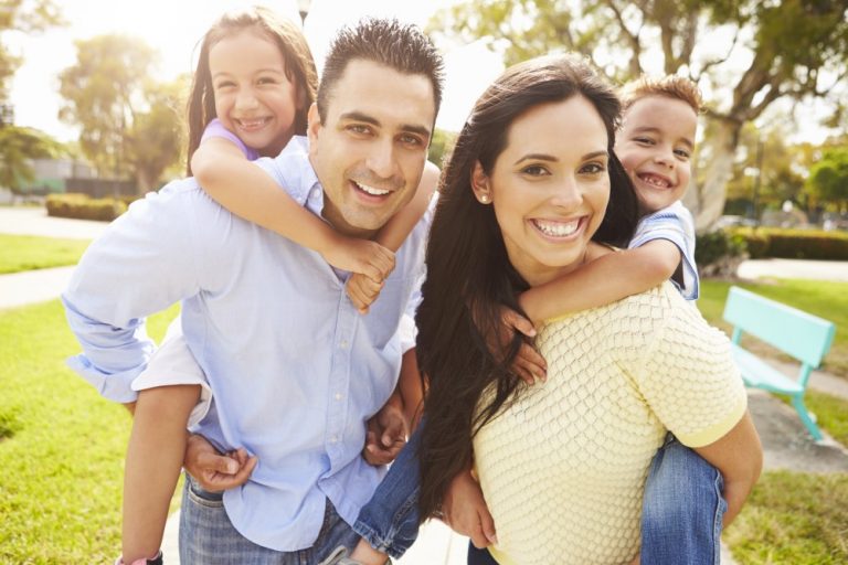 joven familia con dos niños que van a Spring Green Family Dental en Katy, TX para sus servicios de odontología infantil.